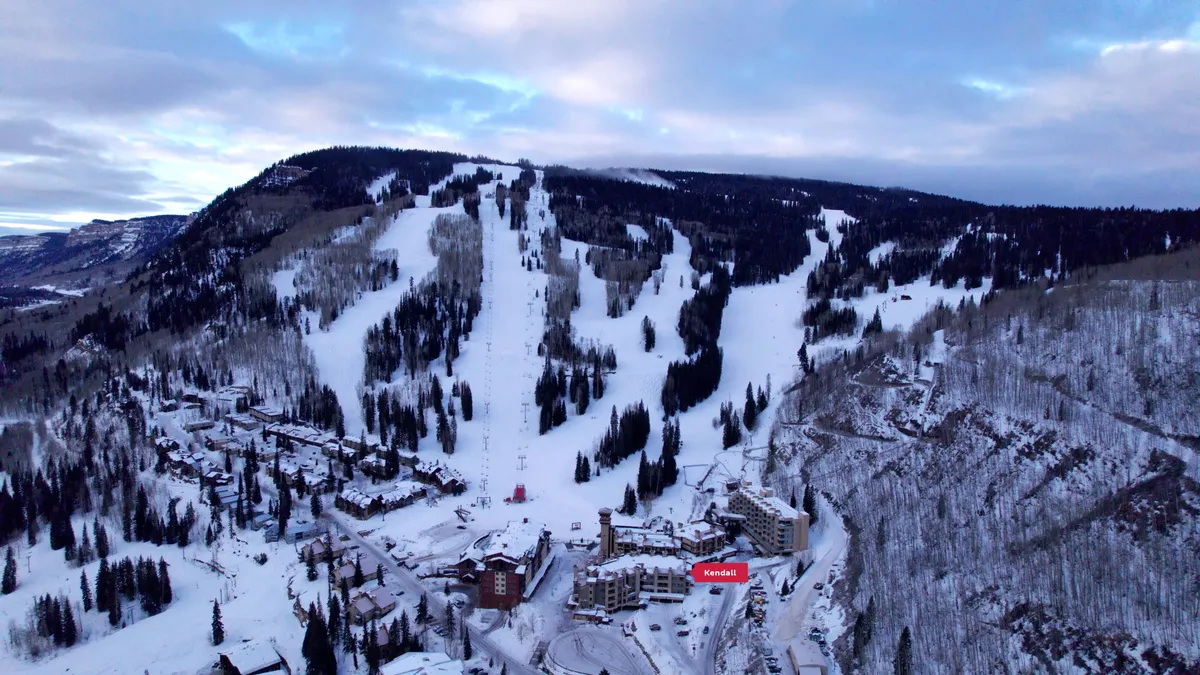 A breathtaking winter exterior view featuring ski slopes, resort buildings, and snow-covered trees beneath a vibrant sky. The scene captures both the excitement of mountain recreation and a peaceful, restorative setting.