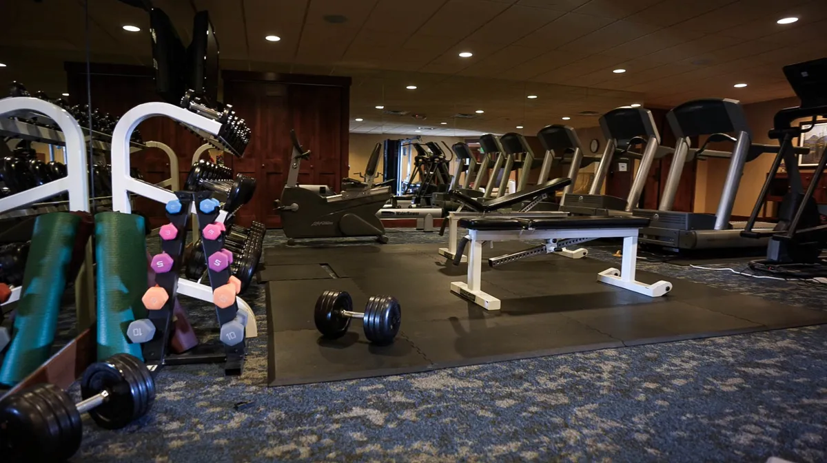 A bright, well-equipped fitness center with dumbbells, treadmills, a weight bench, and exercise mats, arranged to create an energizing and motivating environment for guests to work out during their stay.