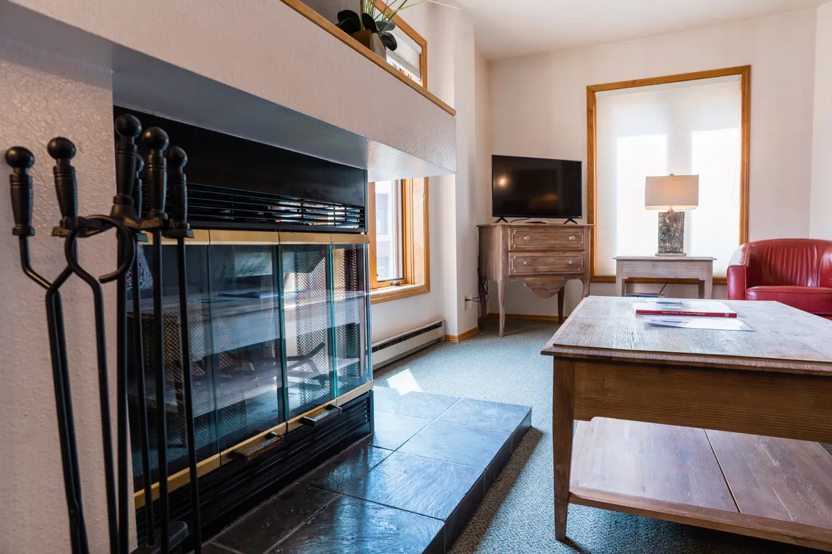 A corner of the living room centered around a fireplace, with a red chair and coffee table nearby. The arrangement is intimate and inviting, suited for quiet evenings or casual gatherings. The TV and decor add to the homey, welcoming mood.