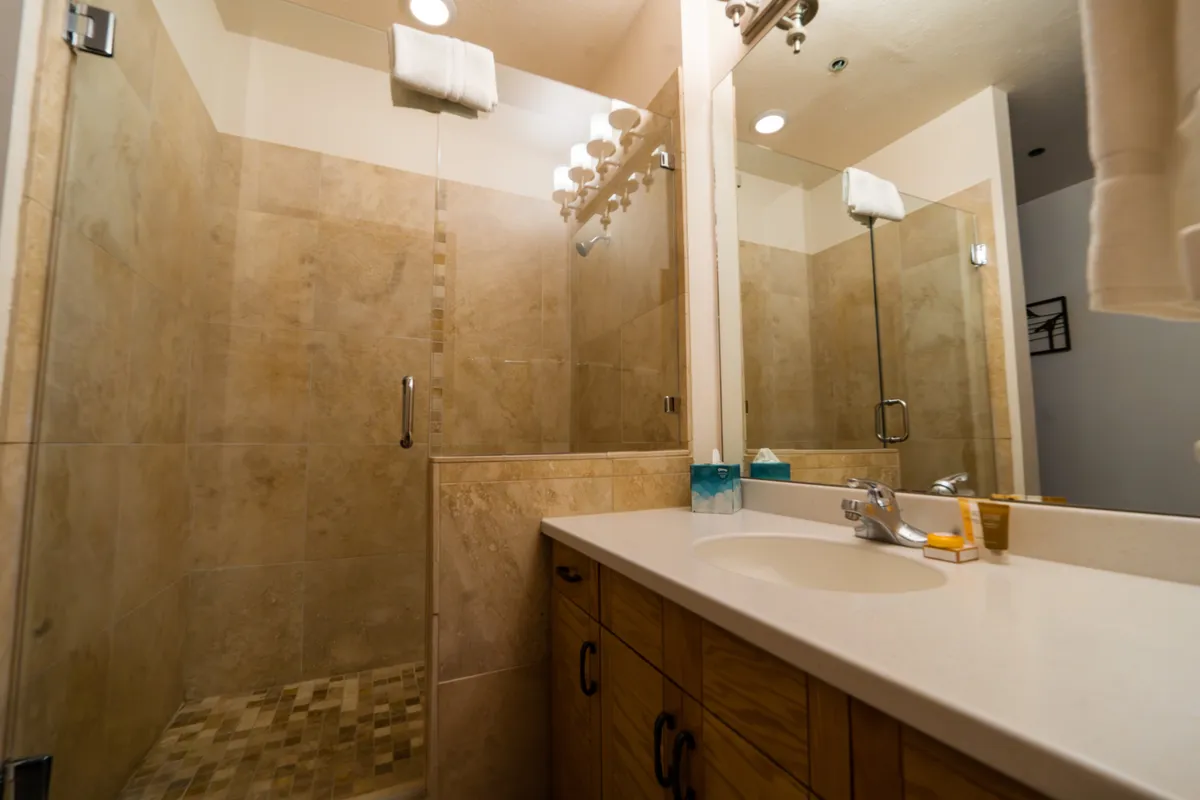 A modern bathroom with a glass shower enclosure, a sleek vanity with sink, and a mirrored wall. The serene color palette and clean lines create an inviting atmosphere for relaxation and self-care.
